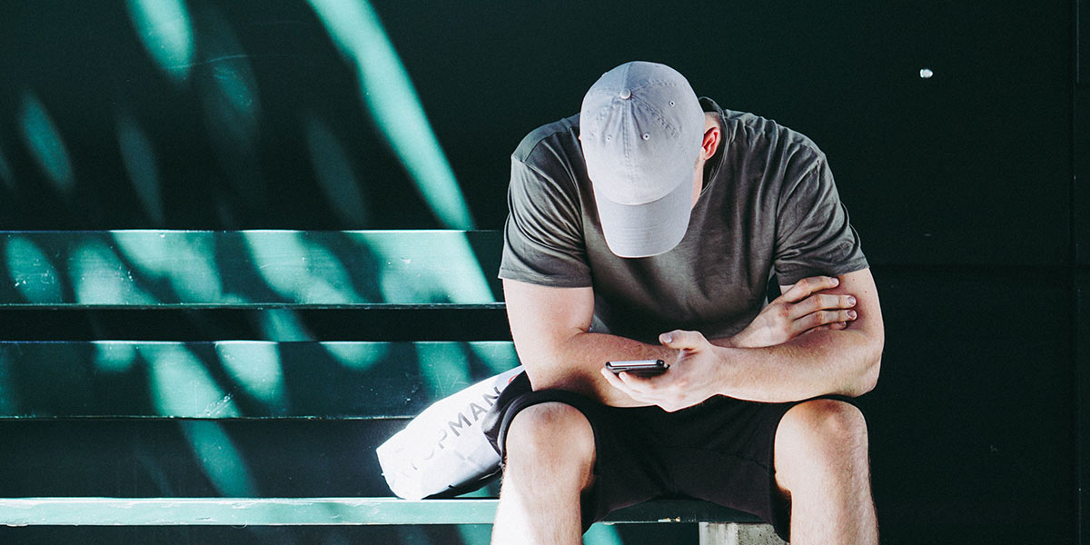 man sitting on bench looking at cell phone