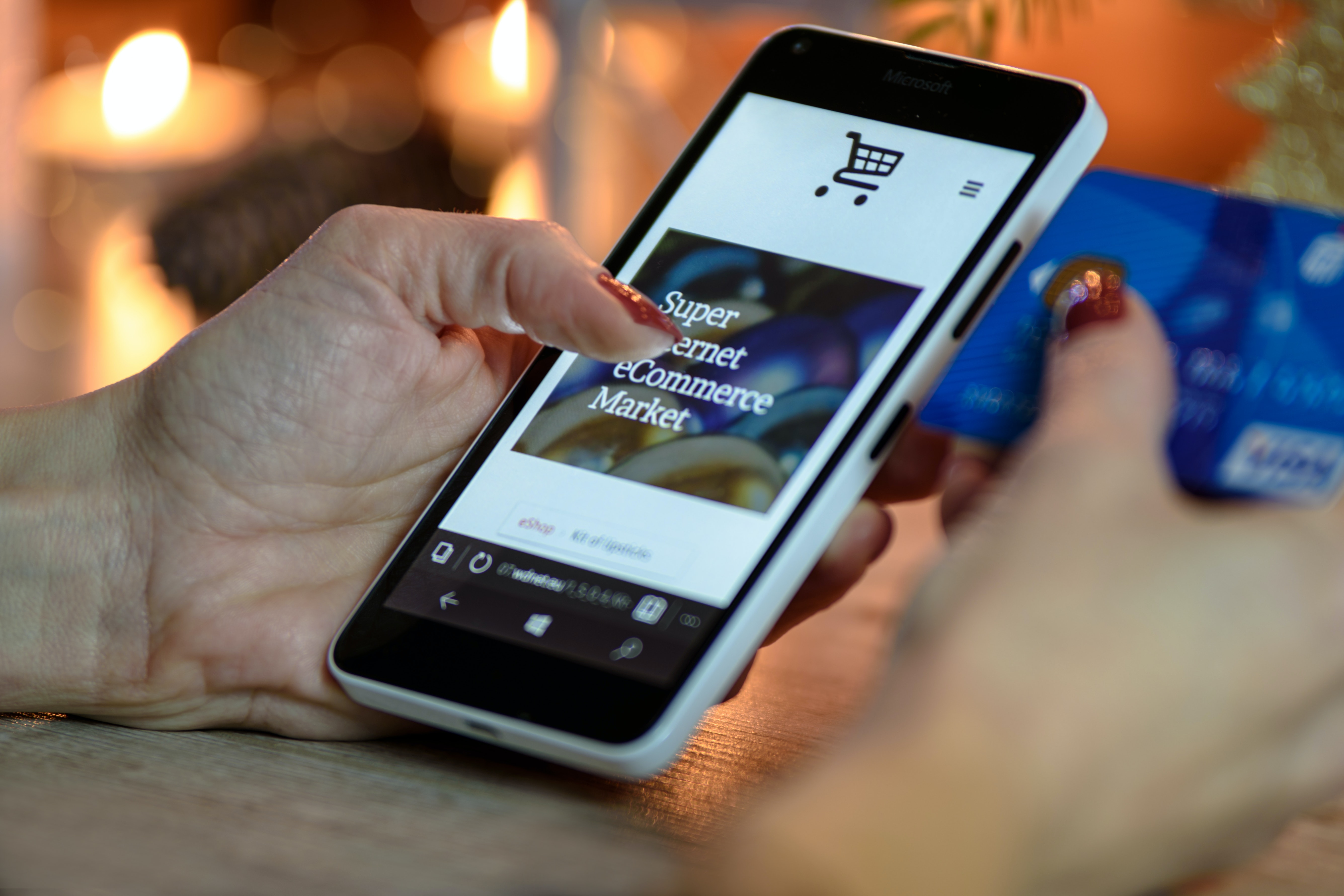 Person using black and white smart phone and holding blue card